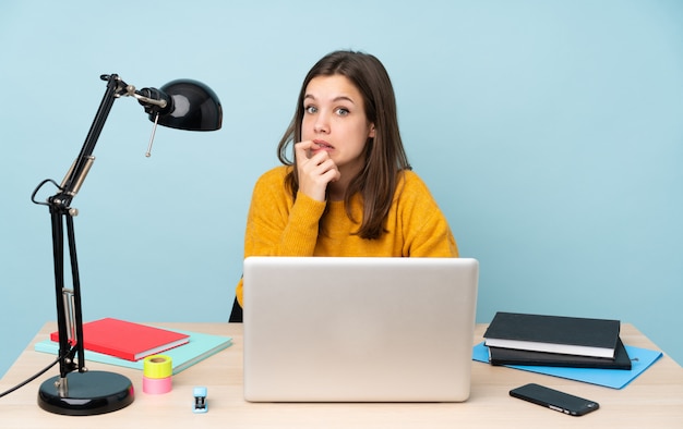 Studentenvrouw die in haar huis bestuderen dat op blauwe zenuwachtig en doen schrikken muur wordt geïsoleerd