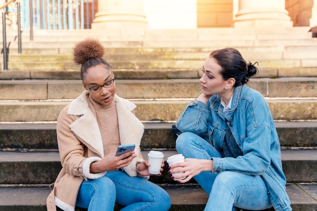 studentenvrouwen praten aan de telefoon, lachen en drinken koffie en sociale media verdelen mensen