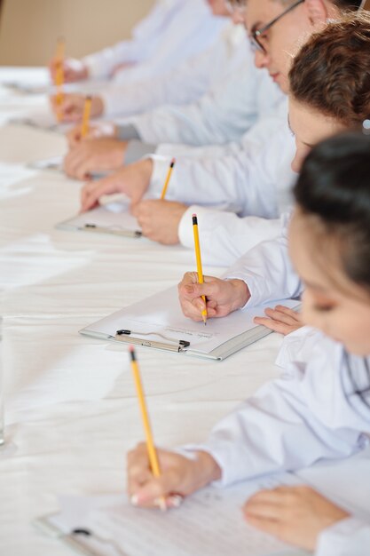 Students attending lesson in medical school and taking notes in notebooks