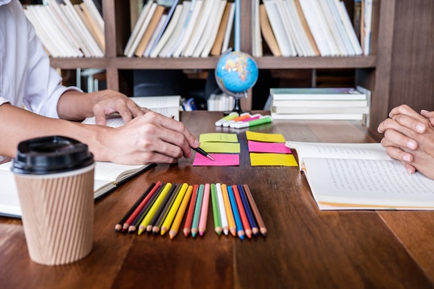 Photo students campus helps friend catching up workbook and learning tutoring