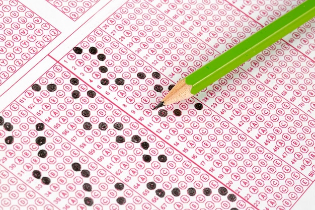 Students hand doing exams quiz test paper with pencil drawing selected choice on answer sheets at school