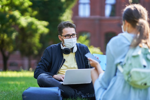 Students hanging out in the campus wearing protective masks and keeping distance due to coronavirus pandemic