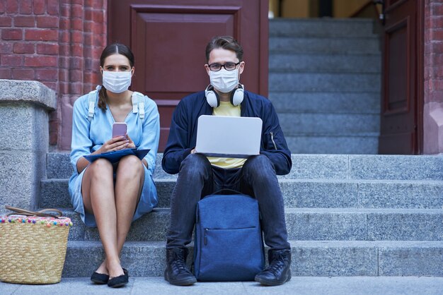 Students hanging out in the campus wearing protective masks and keeping distance due to coronavirus pandemic