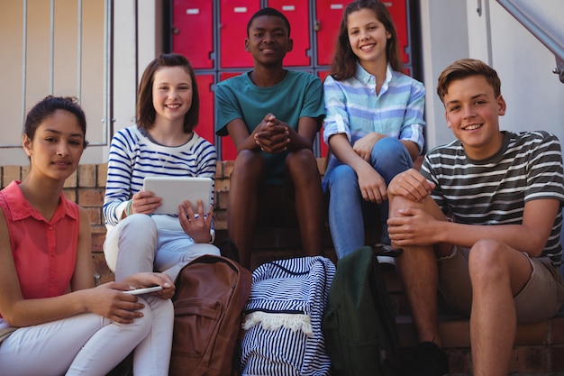 Students holding mobile phone and digital tablet on staircase