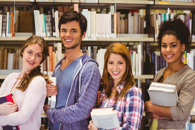 Students in a line smiling at camera holding books