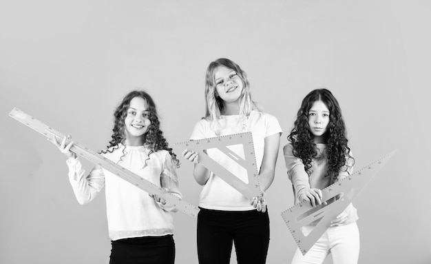 三角形と定規を持った3人の女の子が学校に戻る試験の準備をしている学生STEM学校は数学と人々の概念幾何学的形状現代の教育概念