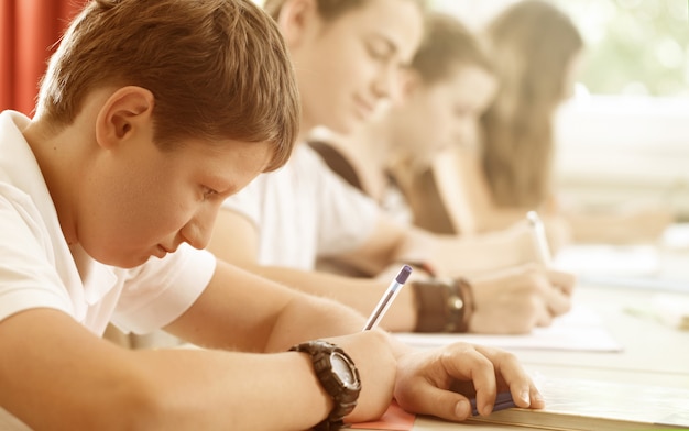 Foto studenti o alunni che scrivono test a scuola concentrati