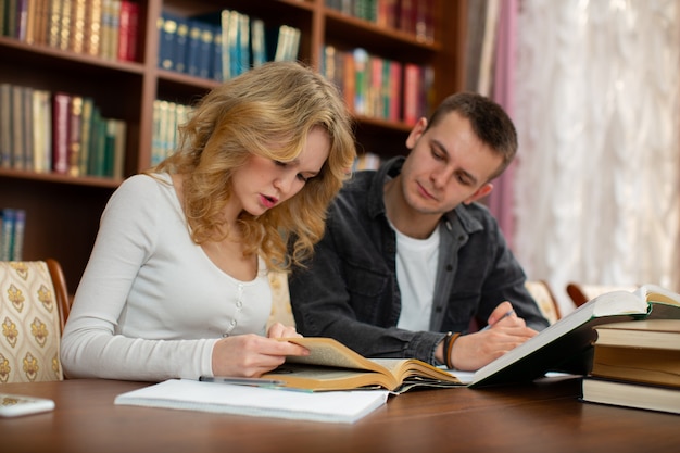 Gli studenti leggono un libro mentre si preparano per un esame in biblioteca