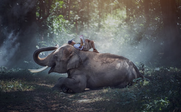 タイの農村の学生タイのスリン県の象と一緒に本を読んでいます。