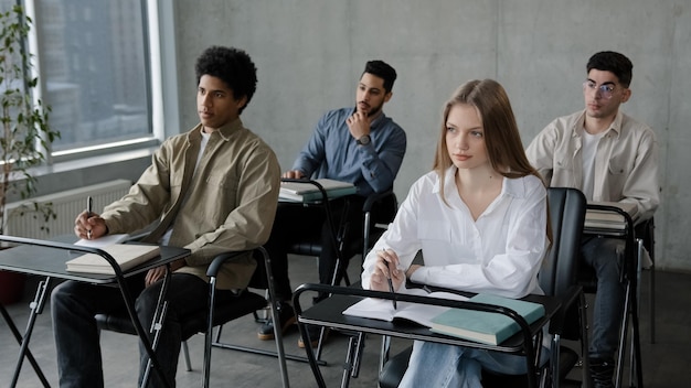 Students sit at desk in classroom attentive listen lecture at seminar write notes prepare for exam