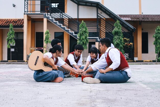 students sitting on the ground and stacking hands together before practicing music at school