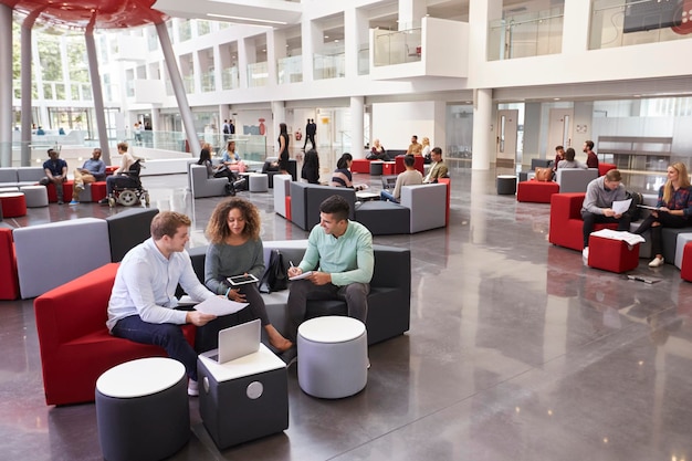 Students sitting in university atrium three in foreground