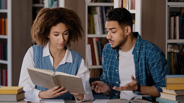 Students studying in library doing homework preparing for exam young girl reads textbook searches