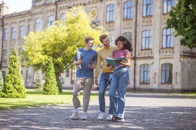 Students. Two guys and a girl walking and discussing future exams