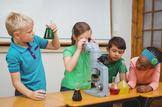 Students using science beakers and a microscope