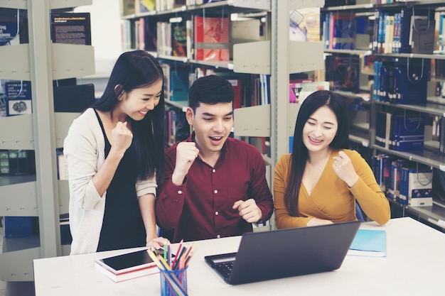 Students with clenched fists while looking at laptop on table