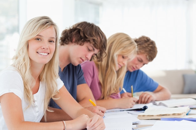 Gli studenti che lavorano come una ragazza sorride e guarda la telecamera