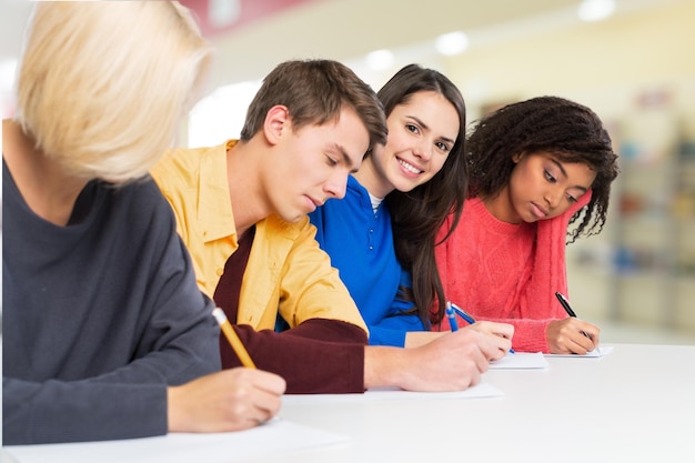 Students writing at high-school exam teens study campus academic class