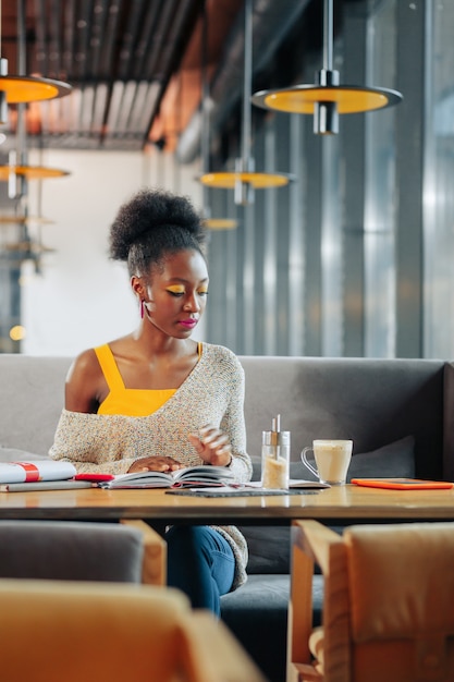 Studeren en drinken Stijlvolle ijverige student die zich druk voelt tijdens het studeren en koffie drinken