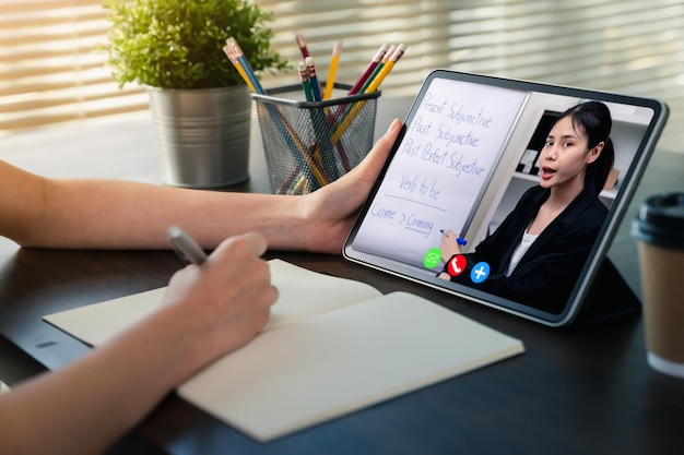 Studeren vanuit huis concept, jonge vrouw kijken les online op digitale tablet met videoconferentie.