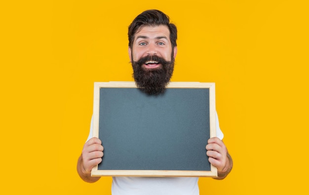 Studio advertisement of smiling man bearded man at advertisement blackboard with copy space