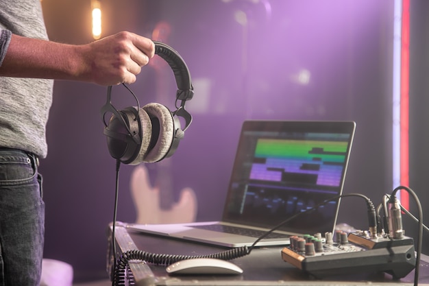 Foto studio audio koptelefoon voor het opnemen van geluid in mannelijke handen op onscherpe studio achtergrond van muziekstudio.