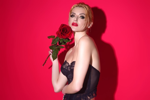 Studio beauty portrait of young beautiful sexy woman with red rose flower