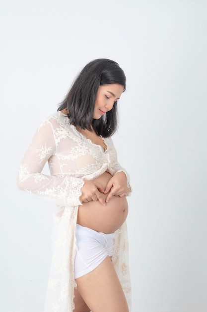 Studio fashion portrait pregnant happy woman. Pregnant young mother portrait, caressing her belly and smiling close-up. Healthy Pregnancy concept at white room.