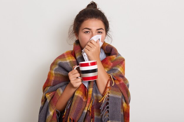 Studio foto van jonge vrouw met zakdoek en beker in handen.