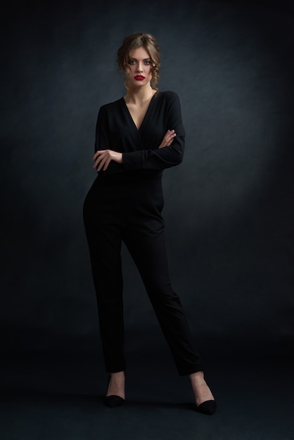 Studio frontview of young confident woman wearing black stylish suit and posing in front of camera. 