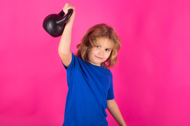 Studio geïsoleerd portret van sportief kind Schattig kind jongen armspieren oppompen met kettlebell Fitness kinderen met halters