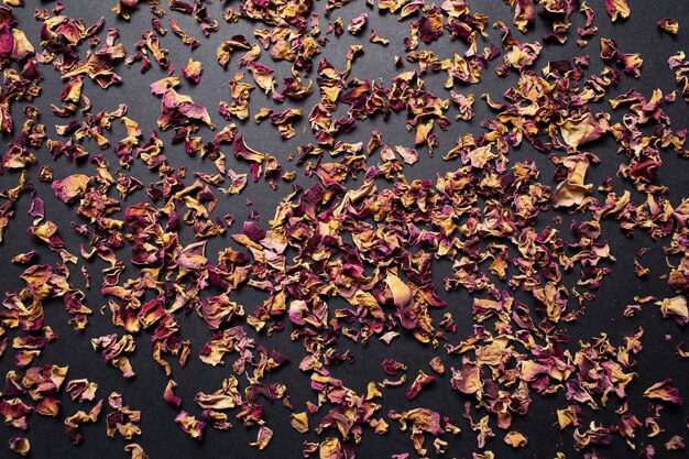Студийное изображение сушеных листьев чайной розы на темном фоне.