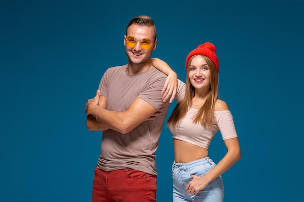 Studio lifestyle portrait of two best friends hipster wearing stylish bright outfits, hats, denim shorts and glasses, going crazy and having great time together.