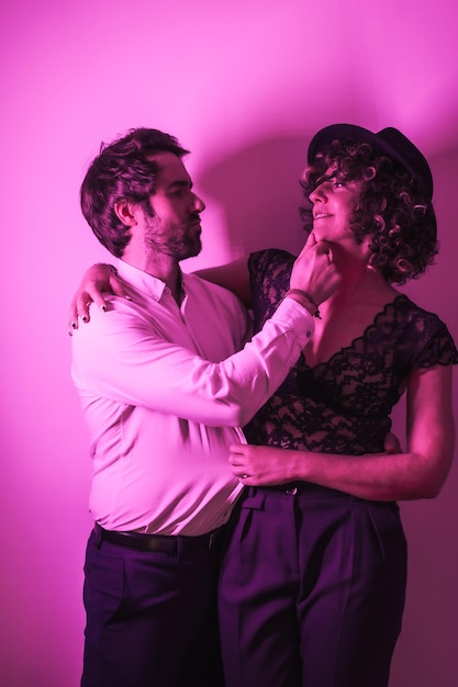 ピンクのネオンライトで照らされたバレンタインデーに抱かれた愛の若いカップルのスタジオライフスタイル