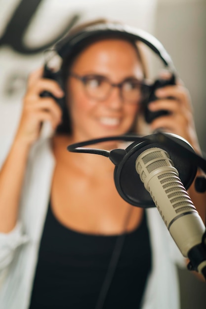 Studio microfoon in focus jonge talk show presentatrice met koptelefoon op de achtergrond