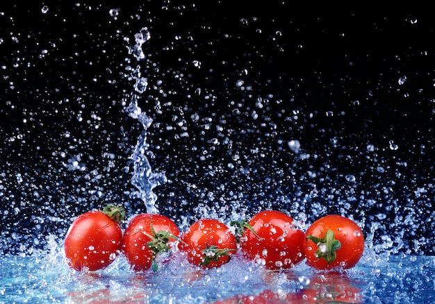 Studio opname met bevriezen beweging van cherry tomaten in water splash op zwarte achtergrond