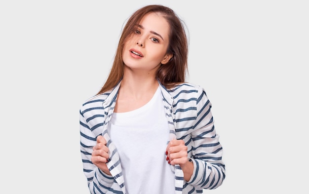 Studio-opname van een knappe jonge student glimlacht positief gekleed in een casual gestreept shirt, kijkend naar de camera geïsoleerd op een witte studiomuur