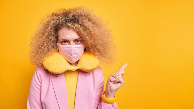 Foto studio-opname van een mooie jonge vrouw met krullend haar kijkt serieus naar de camera