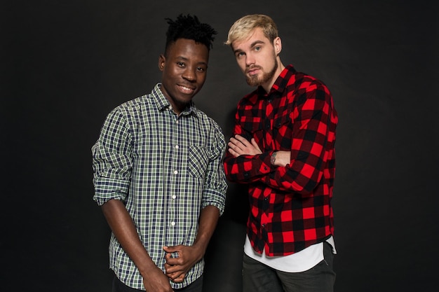 Studio-opname van twee stijlvolle jonge mannen die plezier hebben in een knappe bebaarde hipster in een shirt in een kooi-standi...