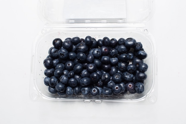 Studio photo of plastic box with fresh blueberries, isolated on white.