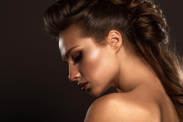 Studio photo sensual woman with gorgeous long dark hair and bright glow make up with naked shoulders