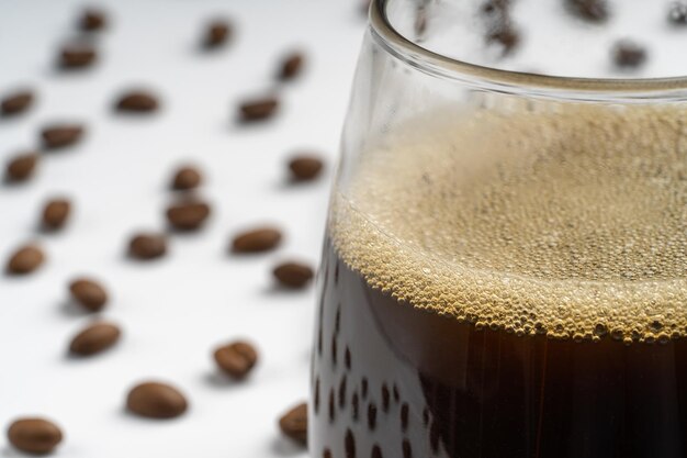 Foto foto di studio con sfondo bianco di un bicchiere con caffè nero e fagioli intorno