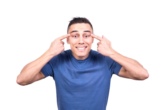 Studio photo with white background of a man stretching the skin over his eyes pretending to be asian