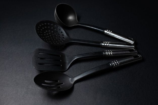 Studio picture of black eco plastic kitchen utensils, on the dark table.