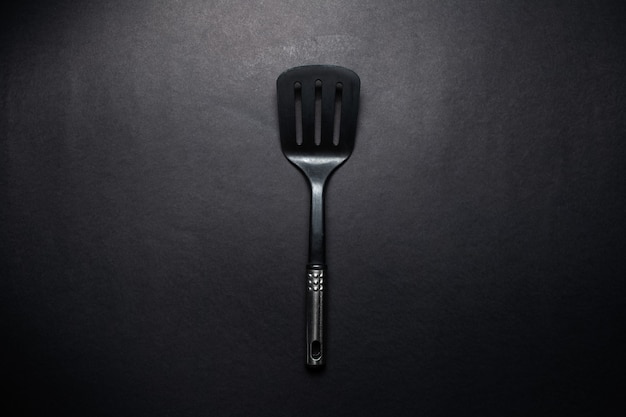 Студийное изображение черного пластикового шпателя с хромированной ручкой.