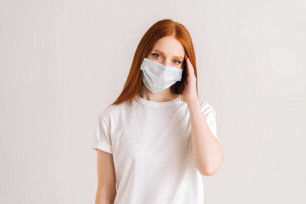 Studio portrait of attractive young woman wearing casual tshirt and protective face mask looking at