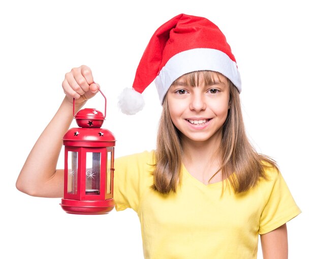 Studio portrait of a beautiful caucasian girl wearing Santa Claus hat isolated on white background Holiday Christmas concept funny child holding red lantern she is laughing and looking very happy