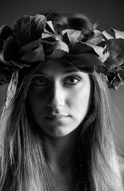 Studio portrait of a beautiful girl with a laurel oak leaves crown