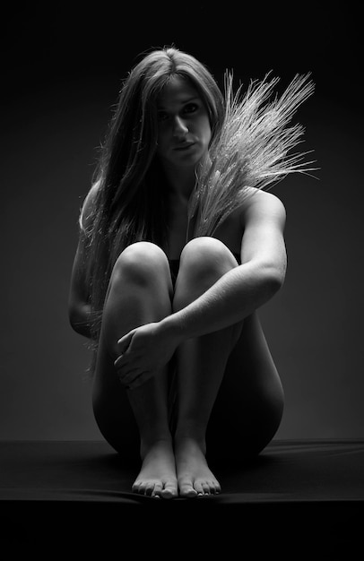 Studio portrait of a beautiful girl with sheafs of wheat