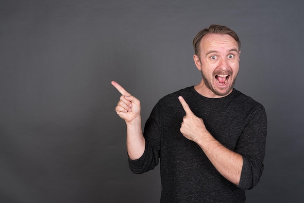 Studio portrait of blonde Caucasian man pointing fingers to copy space